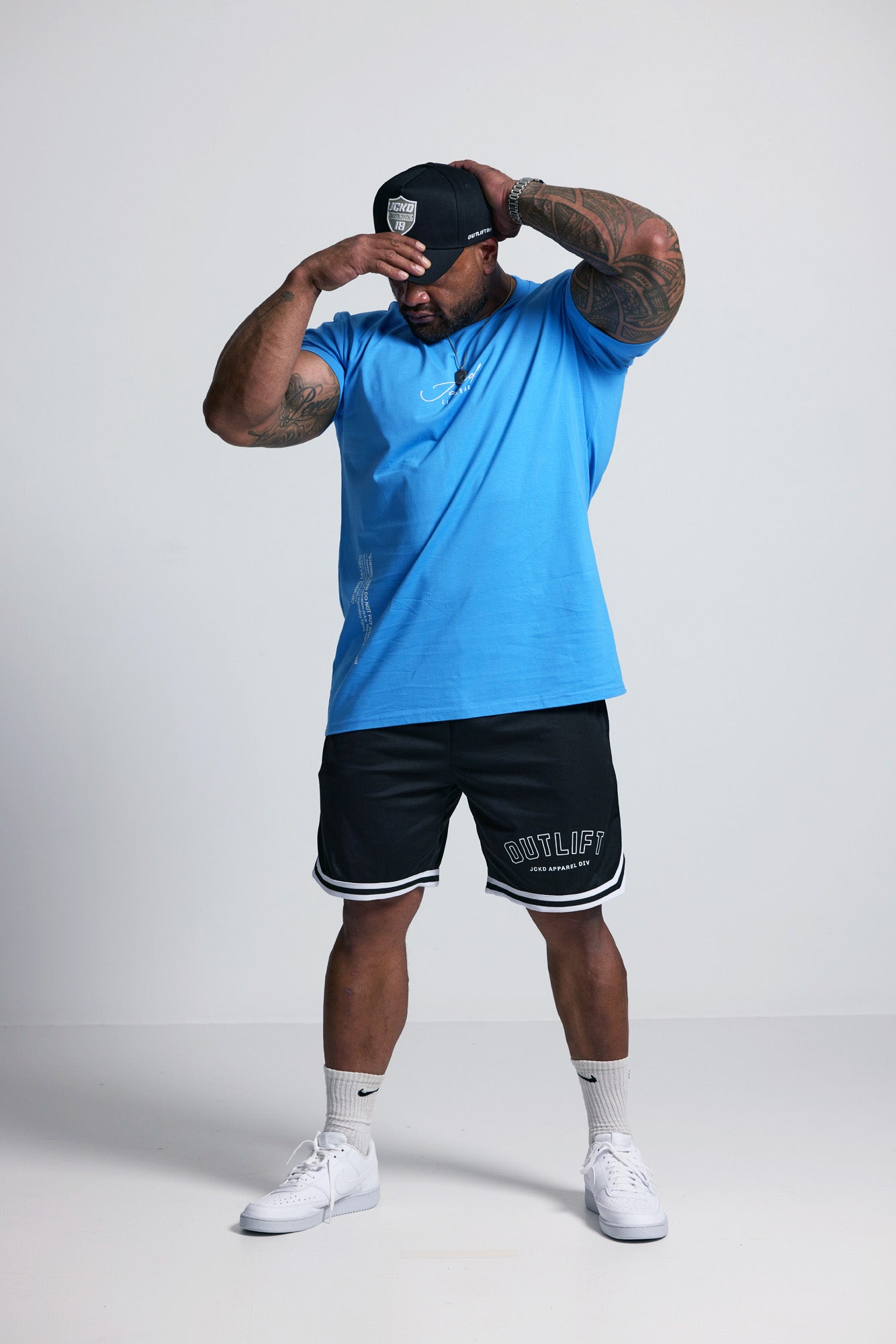Person wearing a blue t-shirt, black shorts, and white sneakers on a plain background