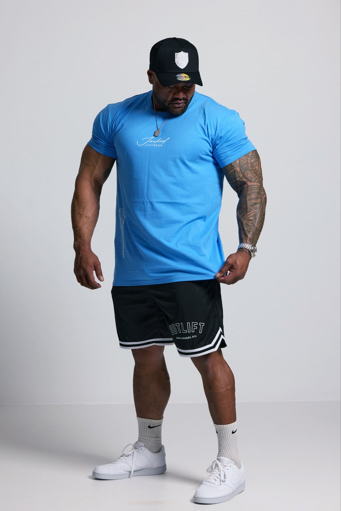 Person wearing a blue t-shirt, black shorts, and white sneakers on a plain background