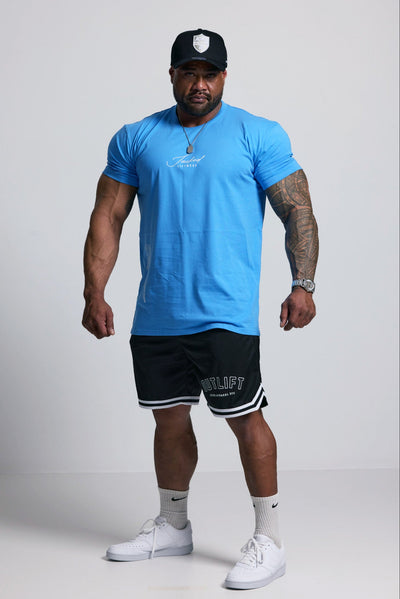 Man wearing a blue t-shirt, black shorts, and white sneakers on a white background