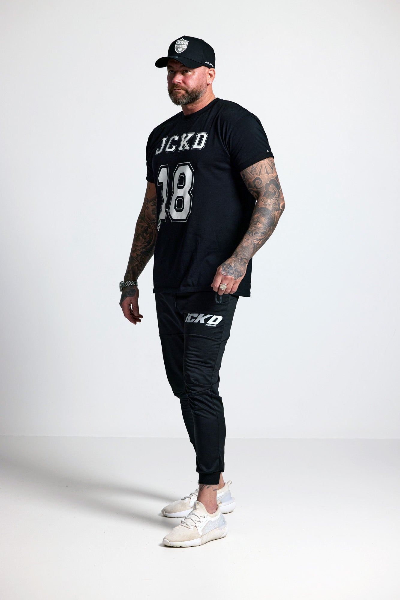 Man wearing black t-shirt and jogger pants with visible branding on a white background