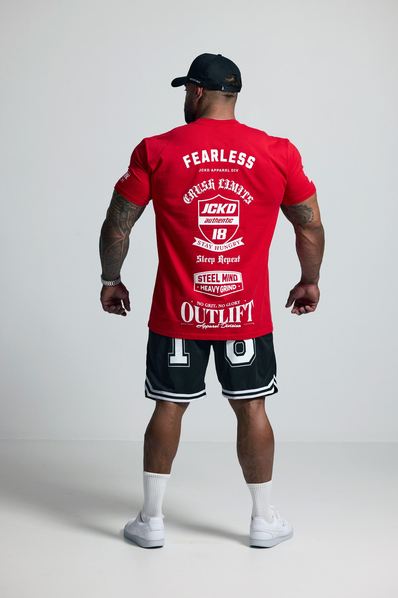 Person wearing a red t-shirt with branding and text, standing against a plain background