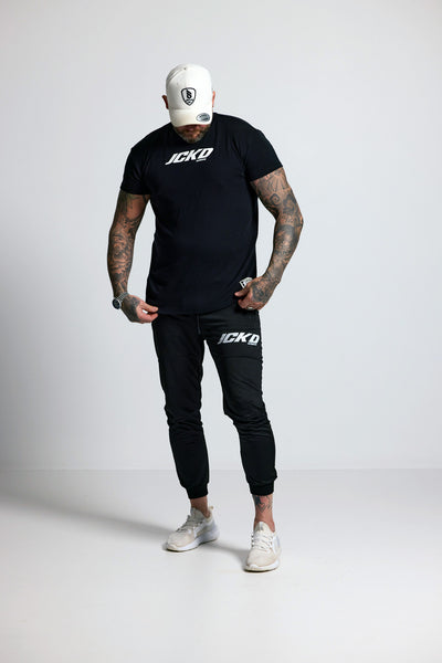 Person wearing black t-shirt and pants with 'JCKD' branding on a white background