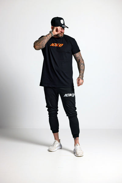 Person wearing a black t-shirt and jogger pants with 'JCKD' branding on a white background