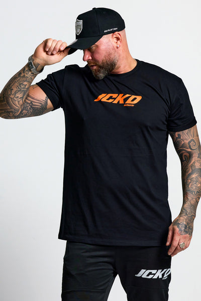 Man wearing a black t-shirt with 'JCKD' logo and matching pants on a white background