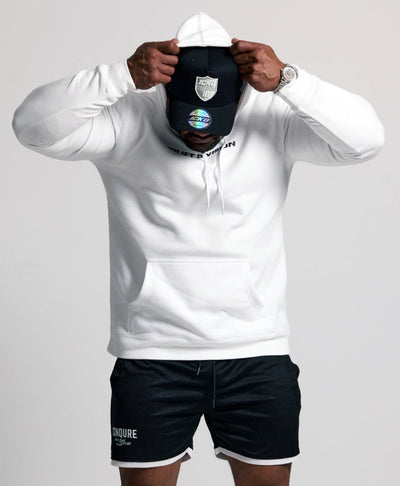 Person wearing a white hoodie, black shorts, and white sneakers on a plain background