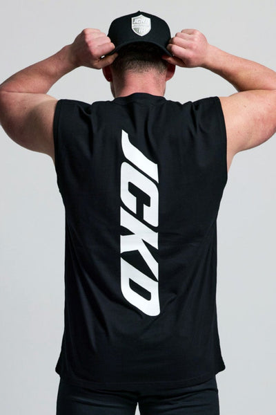 Person wearing a black sleeveless shirt with 'JEKO' branding, black pants, and white sneakers on a light gray background.