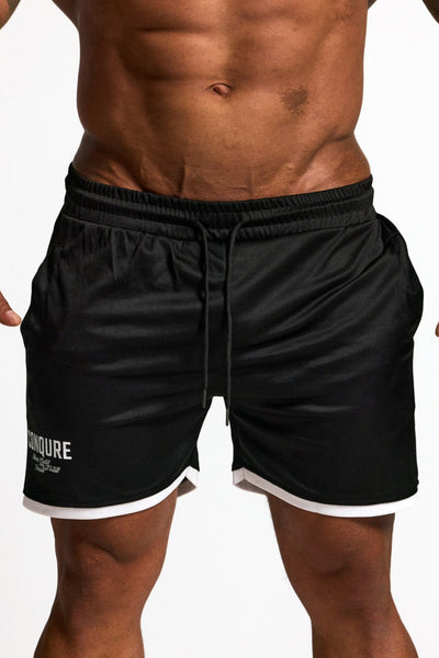 Person wearing black athletic shorts with a visible brand logo on a white background