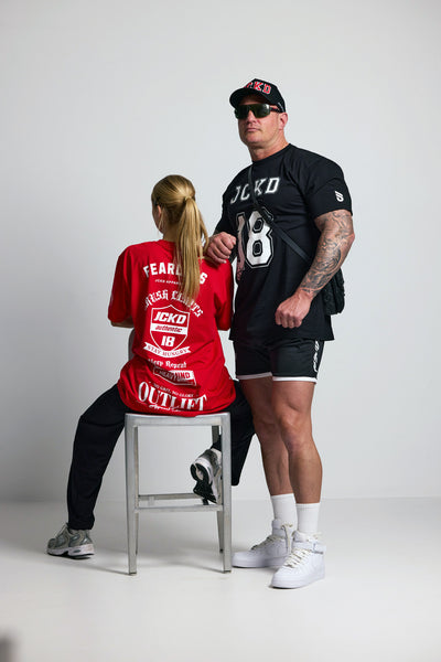 Two people wearing branded clothing with visible logos on a plain background